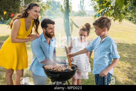 Father and son preparing meat on charcoal barbecue grill Stock Photo