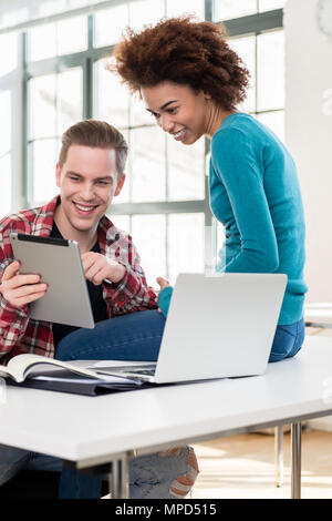 Two happy students watching a funny video on a tablet PC during break Stock Photo
