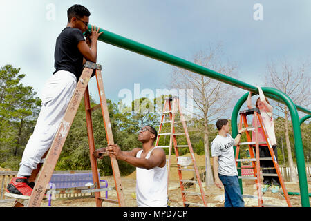Students from Information Warfare Training Command Corry Station in Pensacola, Florida, volunteer to assemble a swingset for Perdido Kids' Park as part of a community relations project. Fifteen students awaiting classes or next duty assignments contribute to park restoration, promoting teamwork, civic engagement, public service, and volunteerism. The project supports local community infrastructure and provides practical training in construction, organization, and coordination for service members. Stock Photo