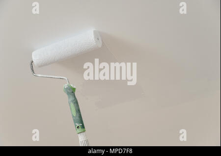 Painting the ceiling and walls. Roller touching the surface and leaving a trail of paint. Stock Photo