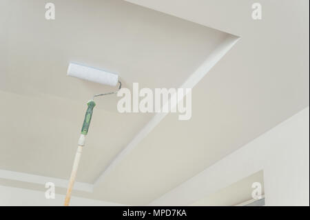 Painting the ceiling and walls. Roller touching the surface and leaving a trail of paint. Stock Photo