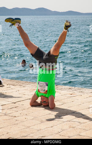 Man exercising by doing a head stand on the pier / waterfront  in the resort of Zadar Croatia Stock Photo