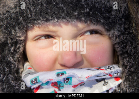 Boy's face with narrowed eyes in  hat and scarf in street close up Stock Photo