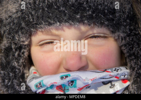 Boy's face with narrowed eyes in  hat and scarf in street close up Stock Photo