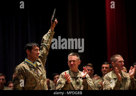 U.S. Army Master Sgt. Josh Horsager, 75th Ranger Regiment, hoists his pistol into the air during an award ceremony recognizing him as one of the Army's best Rangers at Fort Benning, Ga., April 10, 2017. The Colt M1911s are awarded to the winners of the competition each year. Stock Photo