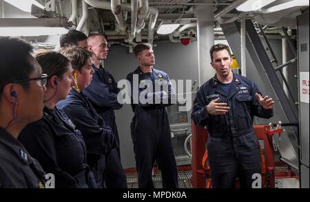 170303-N-RM689-136  SOUTH CHINA SEA (March 3, 2017) Gas Turbine System Technician 2nd Class Andrew Mesenbrink (right), from Killen, Alabama, holds training on gas turbine generators during a tour of an engine room aboard Arleigh Burke-class guided-missile destroyer USS Wayne E. Meyer (DDG 108). Wayne E. Meyer is on a regularly scheduled Western Pacific deployment with the Carl Vinson Carrier Strike Group as part of the U.S. Pacific Fleet-led initiative to extend the command and control functions of U.S. 3rd Fleet into the Indo-Asia-Pacific region. U.S. Navy aircraft carrier strike groups have  Stock Photo