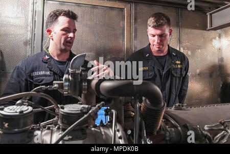 170303-N-RM689-203  SOUTH CHINA SEA (March 3, 2017) Gas Turbine System Technician 2nd Class Andrew Mesenbrink (left), from Killen, Alabama, teaches Lt. j.g. Michael Murphy, from Indianapolis, Indiana, about gas turbine generators during a tour of an engine room aboard Arleigh Burke-class guided-missile destroyer USS Wayne E. Meyer (DDG 108). Wayne E. Meyer is on a regularly scheduled Western Pacific deployment with the Carl Vinson Carrier Strike Group as part of the U.S. Pacific Fleet-led initiative to extend the command and control functions of U.S. 3rd Fleet into the Indo-Asia-Pacific region Stock Photo