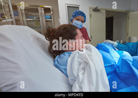 Young woman give childbirth in hospital background. Baby delivery theme Stock Photo