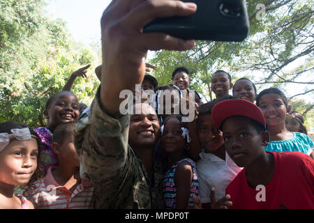 170227-N-WZ792-151 TRUJILLO, Honduras (Feb. 27, 2017) - Equipment Operator 2nd Class Elijah Godbold, a native of Augusta, Ga., Assigned to Construction Battalion Maintenance Unit (CBMU) 202, takes a photo with host nation children during a U.S. Band concert during Continuing Promise 2017 (CP-17) in Trujillo, Honduras.  CP-17 is a U.S. Southern Command-sponsored and U.S. Naval Forces Southern Command/U.S. 4th Fleet-conducted deployment to conduct civil-military operations including humanitarian assistance, training engagements, medical, dental, and veterinary support in an effort to show U.S. s Stock Photo