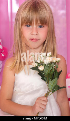 Beautiful tender girl in white festive dress holds bouquet of flowers. Over pink background. Stock Photo
