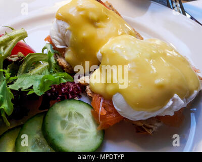 Egg Benedicts with Salmon served with cucumber and salad. Organic Food. Stock Photo