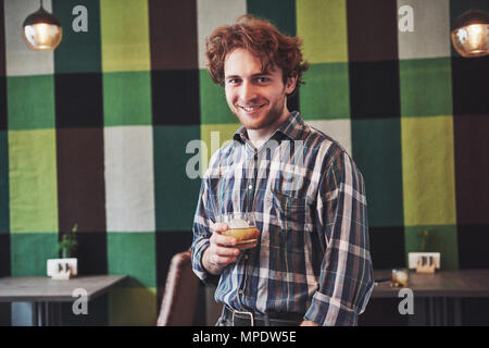 Funny guy holding a glass of whisky and posing against vintage wallpaper Stock Photo