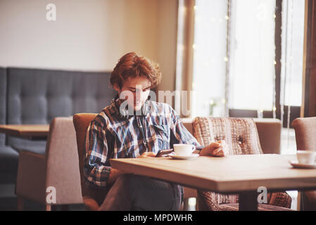 Happy man proprietor of cozy cafe rejoice in own success while sitting with touch pad at dining table, smiling male holding digital tablet and thinks about something good during lunch in coffee shop Stock Photo