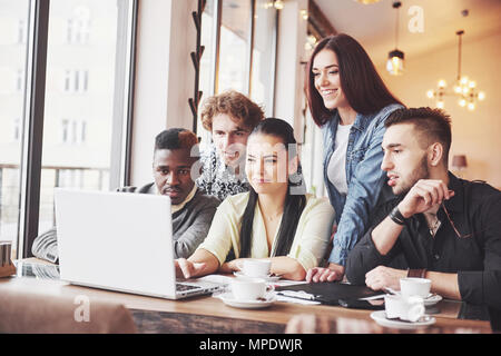 Multi ethnic business people, entrepreneur, business, small business concept, Woman showing coworkers something on laptop computer as they gather around a conference table Stock Photo