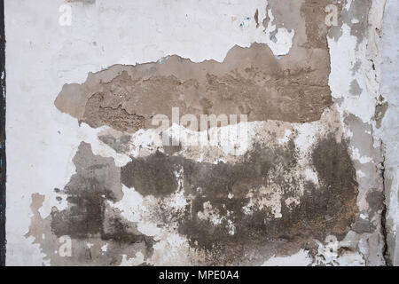 Abstract background of the old wall: brown stains of clay and cement stains from under the fallen white stucco. Stock Photo