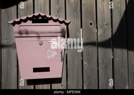 Vintage metal mailbox on a wooden fence wall made of a brown board. Stock Photo