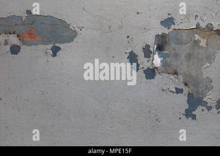 Abstract background of stains of red and blue paint of elongated form fallen plaster on the gray wall. Stock Photo