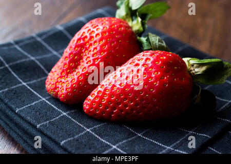 Fresh Organic Ripe Two Strawberries with Leaves on Dark Surface with Tablecloth. Fuit Concept. Stock Photo