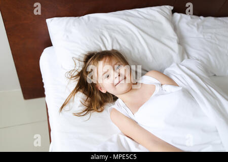 Little girl lying in bed and smiling in morning. Stock Photo