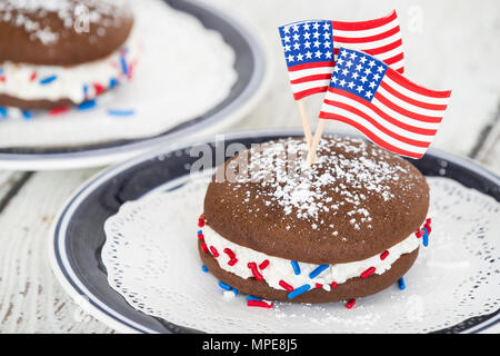 Whoopie pie or moon pie, chocolate cake dessert filled with creamy frosting. Decorated with American flags and red, white, and blue sprinkles in celeb Stock Photo