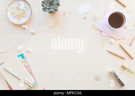 Female home office desk table in pastel tones. Workspace with notebooks, cup of coffe and decorations on light wooden background with copy-space. Flat Stock Photo