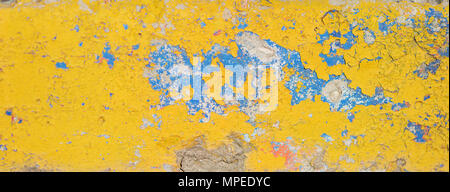 Old cracked wall painted with bright yellow and blue paint. Grunge peeling background Stock Photo