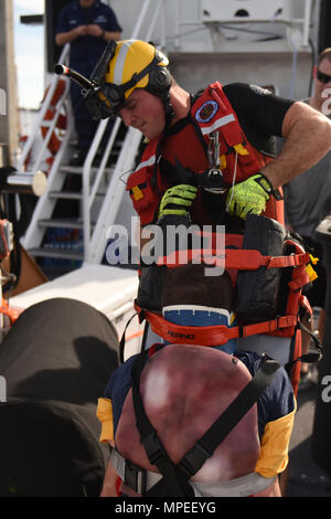Petty Officer 2nd Class Lyman Dickinson, an aviation survival technician at Coast Guard Sector San Diego, maneuvers a simulated victim onto the deck for transport during a mass casualty at sea training session on board Coast Guard Cutter Petrel at Sector San Diego on February 8, 2017. The training was aimed at preparing rescue swimmers to save lives by handling multiple casualties in close quarters on an unfamiliar vessel at sea. (U.S. Coast Guard photo by Petty Officer 3rd Class Joel Guzman/released) Stock Photo