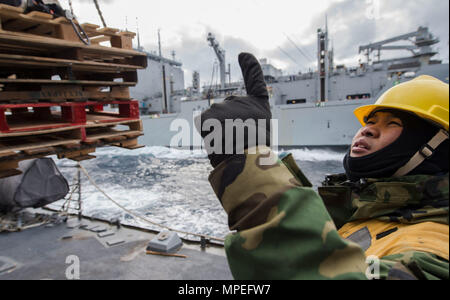 170212-N-HI376-334 SEA OF JAPAN (Feb. 12, 2017) Boatswain’s Mate 2nd Class Laurence George Cerezo, assigned to the forward-deployed Arleigh Burke-class guided-missile destroyer USS McCampbell (DDG 85), directs cargo lift operators during a replenishment-at-sea with the Military Sealift Command (MSC) Dry Cargo and Ammunition Ship USNS Charles Drew (T-AKE 10). McCampbell is on patrol in the U.S. 7th Fleet area of operations in support of security and stability in the Indo-Asia-Pacific region. (U.S. Navy photo by Mass Communication Specialist 2nd Class Jeremy Graham/Released) Stock Photo