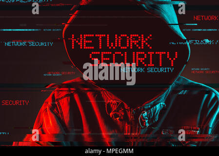 Network security concept with faceless hooded male person, low key red and blue lit image and digital glitch effect Stock Photo