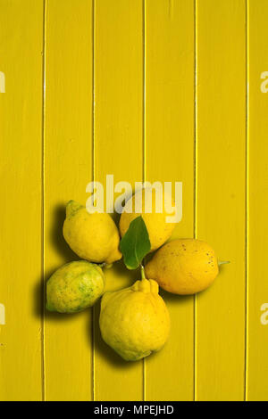 Five lemons on yellow painted wood background vertical copy space. Stock Photo