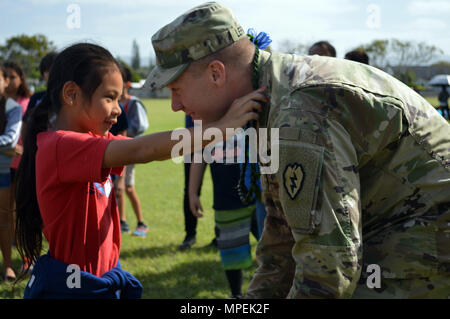 Staff Sgt. Wesley Lefavour, a section leader assigned to 3rd Squadron, 4th Cavalry Regiment, 3rd Brigade Combat Team, 25th Infantry Division, receives a ti leaf lei from a student at Ka’ala Elementary School, Wahiawa, Hawaii, on Feb. 1, 2017. Lefavour described Army life, and let students to wear the Improved Outer Tactical Vest (IOTV) and Advanced Combat Helmet (ACH) during the school’s career day. (U.S. Army photo by Staff Sgt. Armando R. Limon, 3rd Brigade Combat Team, 25th Infantry Division) Stock Photo