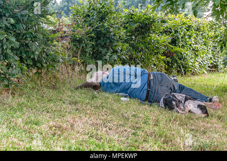 a man sleeping with his dog on a piece of pasture Stock Photo