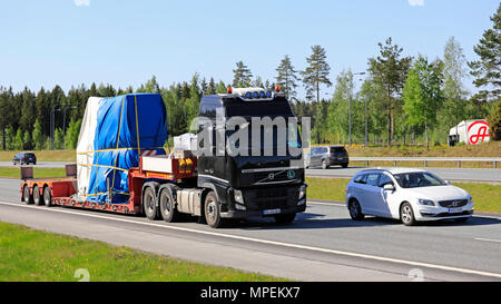 Black Volvo FH 540 semi trailer hauls industrial object as oversize load among motorway traffic on a sunny day of summer in Salo, Finland - May 18, 20 Stock Photo