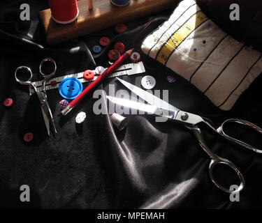 Sewing accessories and tools. Red sewing threads, black scissors, yellow  measuring tape and thimble on a white background. Stock Photo