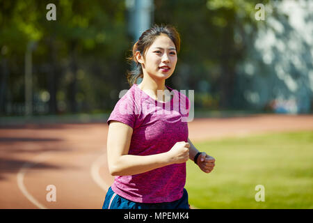 young asian female athlete running training on track outdoors. Stock Photo