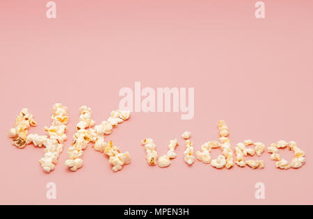 popcorn scattered on pink ground inscription 4k video. Stock Photo