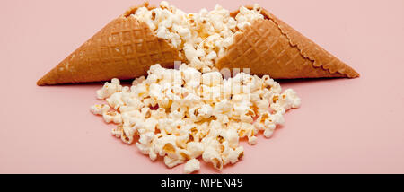 Popcorn in ice cream cones on pink background. Stock Photo