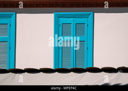 Blue, closed wooden window shutters on beige wall. Stock Photo