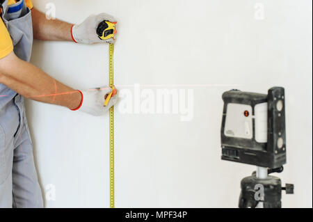 Worker making measurement using laser levels and measuring tape. Stock Photo