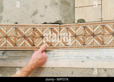 Worker putting tiles on the floor. It installs strips. Stock Photo