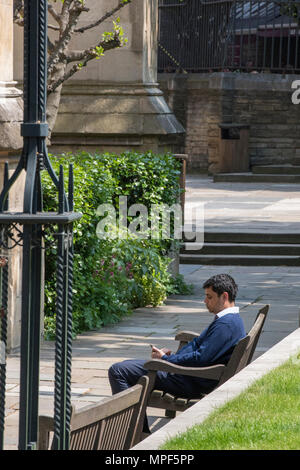 a young businessman or smartly dressed man sitting in a garden relaxing during his lunch break on a bench in the centre of london. taking it easy. Stock Photo
