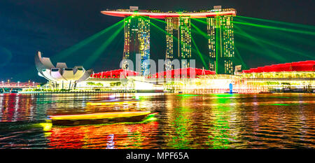 Singapore - April 27, 2018: colorful laser show at night at Marina Bay Sands Hotel Casino and ArtScience Museum with boat on the waters of Marina Bay Waterfront promenade in Marina Bay area Singapore. Stock Photo