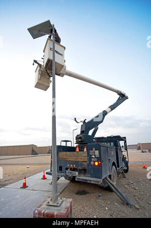 At Al Udeid Air Base, Qatar, a U.S. Air Force electrical systems apprentice adjusts a solar-powered LED light fixture. The fixture stores solar energy in rechargeable batteries, supporting sustainable base operations, reducing utility demand, and enabling efficient maintenance. This demonstrates the 379th Expeditionary Civil Engineer Squadron’s role in ensuring infrastructure reliability, energy conservation, and operational readiness for deployed personnel in a forward operating location. Stock Photo