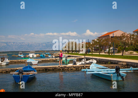 Woman holidaymaker looking at the small fishing boats in the harbour at the medieval walled  town of Nin near Zadar Croatia on the Adriatic coast Stock Photo