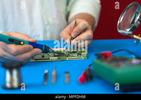 Repair of the video converter board of the TV signal. Soldering of electronic components by an engineer for the modern TVs close-up. Stock Photo