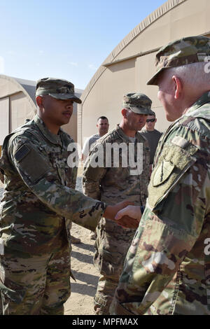 Spc. Raymond Nolan with the 207th Horizontal Constuction company receives a coin from Brig. Gen. Benjamin Adams III, Kentucky's Director of the Joint Staff, Mar. 4 during a visit to Camp Arifjan, Kuwait. Stock Photo