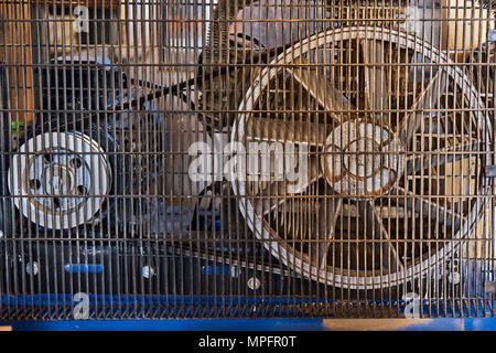 Electrical air compressor with a large fan in front panel behind a metal protective mesh Stock Photo