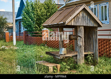 Old wooden well on a brick fence background in the countryside Stock Photo