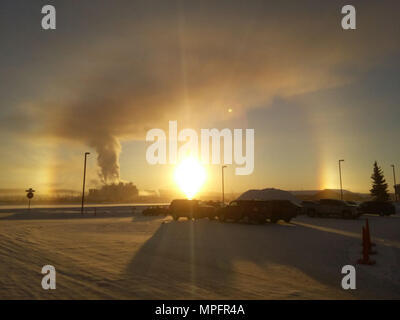The sun rising over Eielson AFB, Alaska, created a sundog or mock Sun, and greeted residents of the interior-Alaska base on this -30° morning, March 9, 2017. According to astronomers, a sundog is formed when sunlight refracts through icy clouds containing hexagonal platecrystals aligned with their large, flat faces parallel to the ground, and since Eielson has a lot of icy clouds hanging around right now, sundogs are a common occurrence and a part of our military life. (U.S. Air National Guard photo by Senior Master Sgt. Paul Mann/Released) Stock Photo