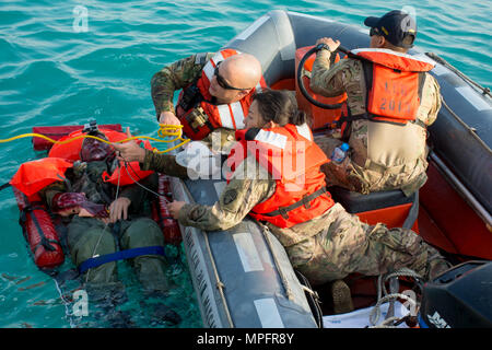 Kuwait-The Soldiers, Watercraft Operators and vessel medic, for the LCU2013 Churubusco- a Landing Craft Utility vessel from Detachment 1, 481st Transportation Company, California, grab a line thrown from the deck to hoist their mock patient from 77th Combat Aviation Brigade, Arkansas, while participating in a personnel recovery mission replicating a downed aircraft scenario, Feb. 13.   (Photo by Army Sgt. 1st Class Suzanne Ringle/Released) Stock Photo